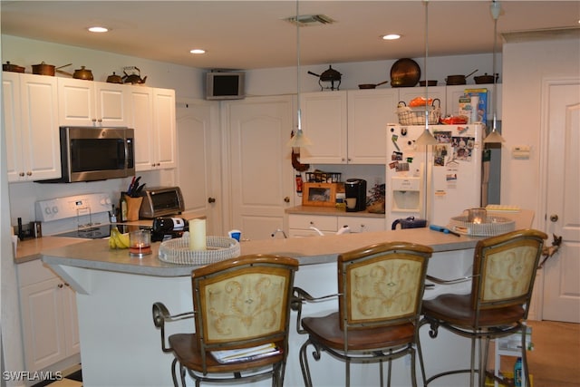 kitchen with white refrigerator with ice dispenser, range, white cabinetry, and a kitchen island