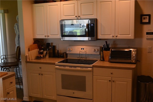 kitchen featuring white electric range oven and white cabinetry