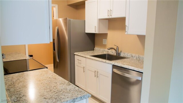 kitchen with white cabinets, stainless steel appliances, sink, and light stone countertops