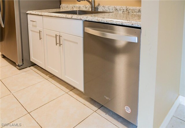 kitchen with white cabinets, dishwasher, light stone countertops, light tile patterned floors, and sink