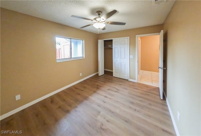 unfurnished bedroom featuring ceiling fan, a textured ceiling, light hardwood / wood-style floors, and a closet