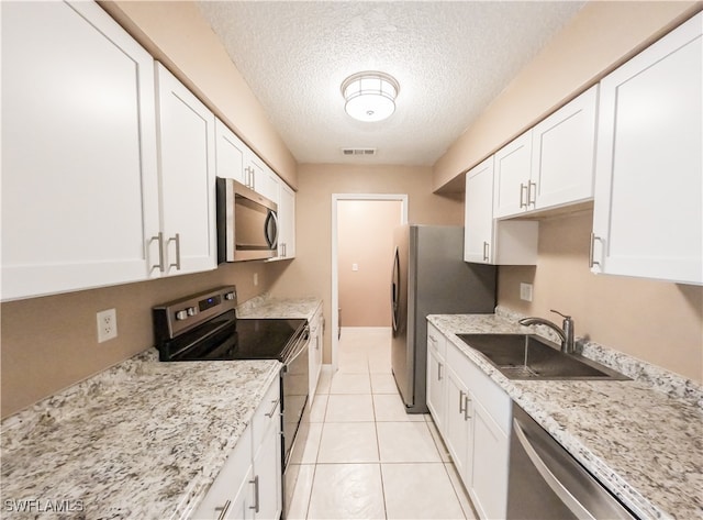 kitchen featuring a textured ceiling, white cabinetry, light tile patterned floors, stainless steel appliances, and sink