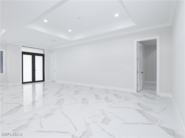 empty room featuring a tray ceiling, french doors, and crown molding