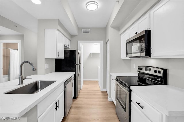 kitchen with appliances with stainless steel finishes, white cabinets, visible vents, and a sink