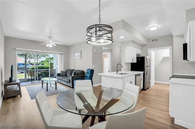 dining area with light wood-style flooring, visible vents, baseboards, and ceiling fan with notable chandelier