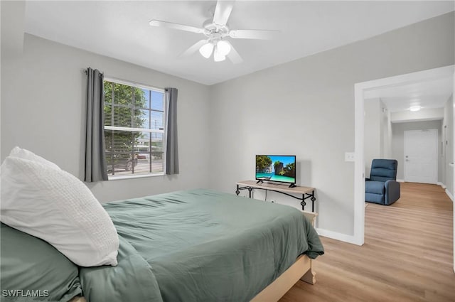 bedroom featuring ceiling fan, light wood-style flooring, and baseboards