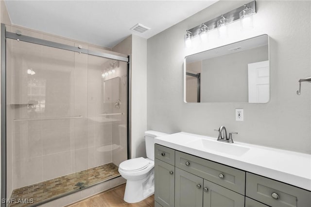 full bathroom featuring toilet, wood finished floors, vanity, visible vents, and a stall shower