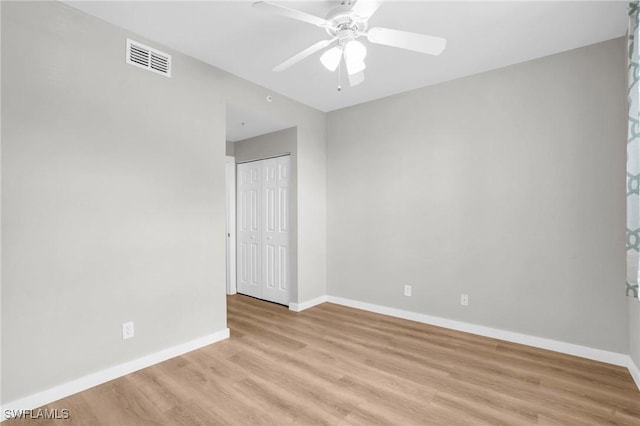 unfurnished room with light wood-style floors, baseboards, visible vents, and a ceiling fan