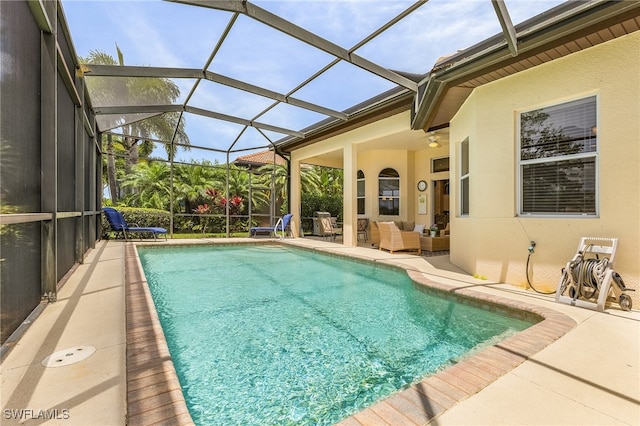 view of swimming pool featuring ceiling fan, a lanai, and a patio area