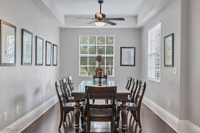 dining space featuring ceiling fan, dark hardwood / wood-style floors, and a tray ceiling