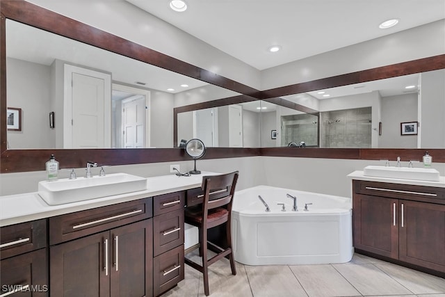 bathroom with a bathtub, double vanity, and tile patterned floors