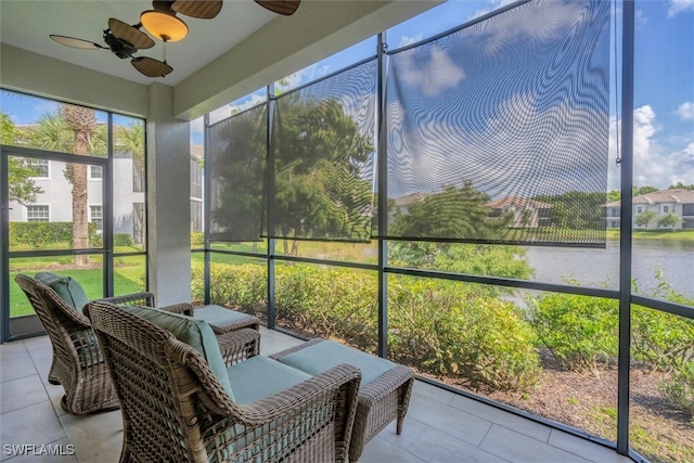 sunroom with ceiling fan and a water view