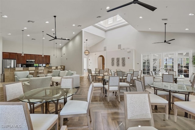 dining space featuring a skylight, french doors, high vaulted ceiling, light parquet flooring, and ceiling fan