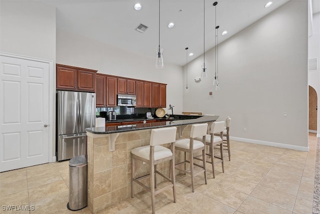 kitchen featuring high vaulted ceiling, hanging light fixtures, appliances with stainless steel finishes, and light tile patterned floors