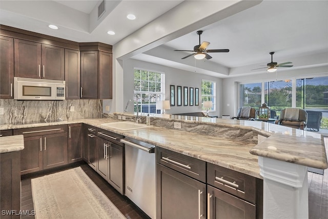 kitchen featuring backsplash, sink, a tray ceiling, ceiling fan, and stainless steel appliances