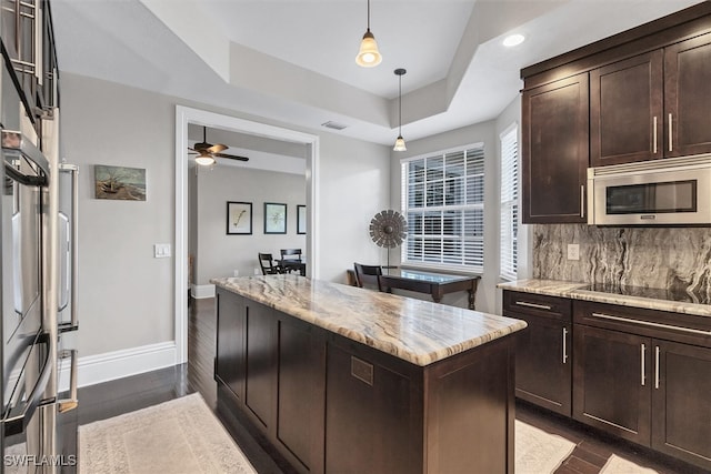 kitchen featuring a raised ceiling, tasteful backsplash, dark hardwood / wood-style floors, and a kitchen island