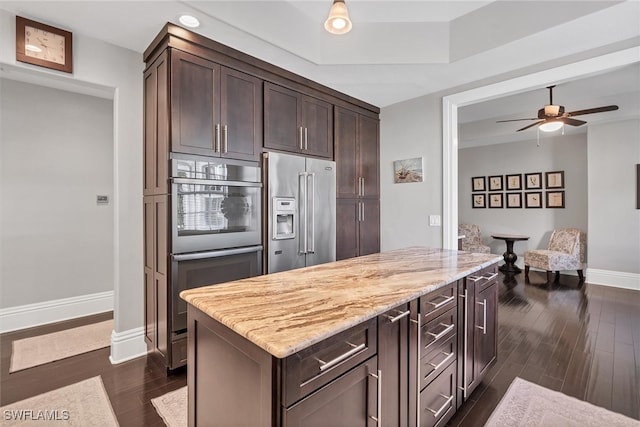 kitchen with ceiling fan, appliances with stainless steel finishes, dark hardwood / wood-style floors, and light stone counters