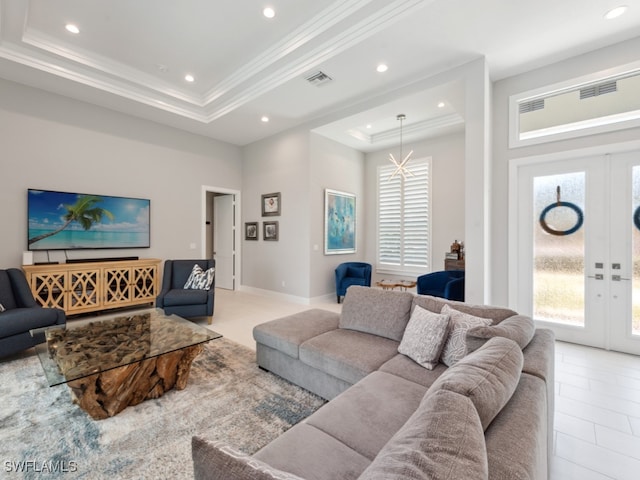 living room featuring an inviting chandelier, french doors, a tray ceiling, and light tile patterned floors