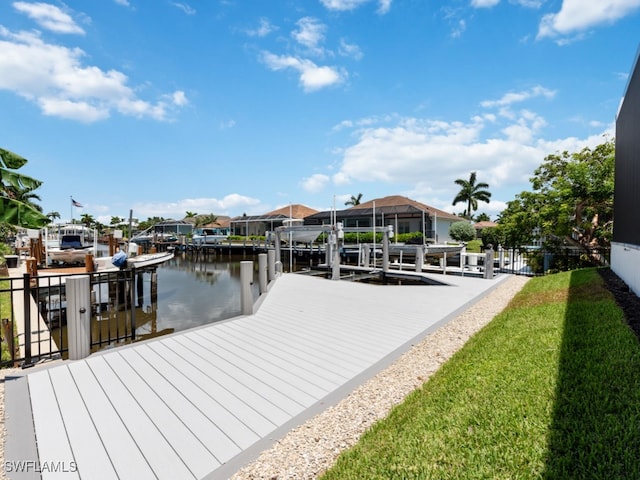 view of dock with a lawn and a water view