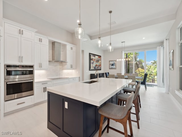 kitchen featuring decorative backsplash, black electric cooktop, sink, stainless steel double oven, and wall chimney range hood