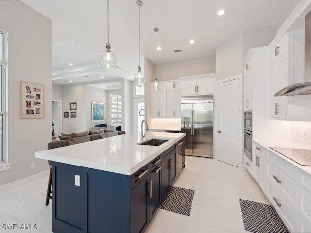 kitchen featuring stainless steel appliances, sink, an island with sink, wall chimney range hood, and white cabinets