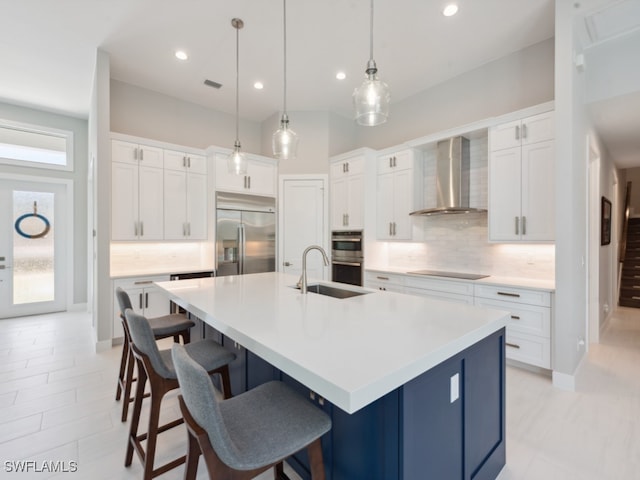 kitchen with wall chimney range hood, backsplash, a spacious island, sink, and stainless steel appliances