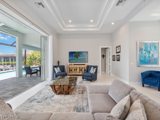 living room with ceiling fan, a raised ceiling, and light tile patterned flooring