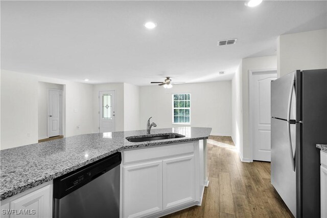 kitchen featuring visible vents, appliances with stainless steel finishes, white cabinetry, a sink, and wood finished floors