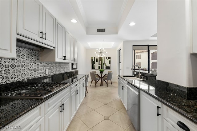 kitchen featuring a tray ceiling, appliances with stainless steel finishes, white cabinets, and dark stone countertops