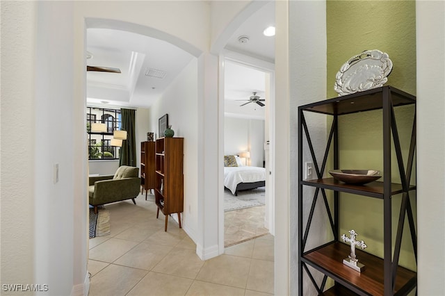 corridor featuring a tray ceiling and tile patterned flooring