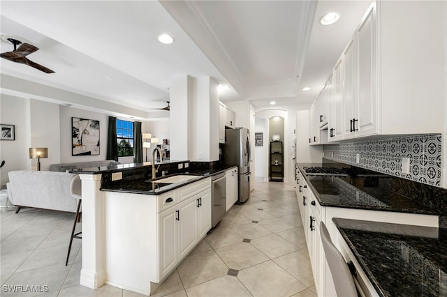 kitchen with a breakfast bar area, stainless steel appliances, white cabinets, ceiling fan, and sink