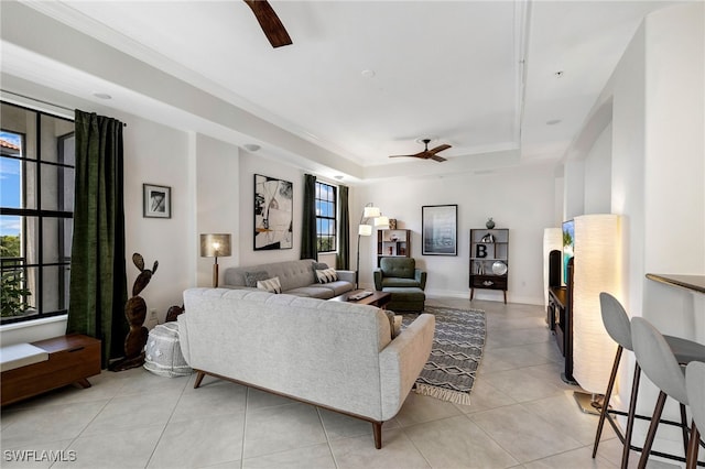 tiled living room with ceiling fan, a raised ceiling, and a healthy amount of sunlight