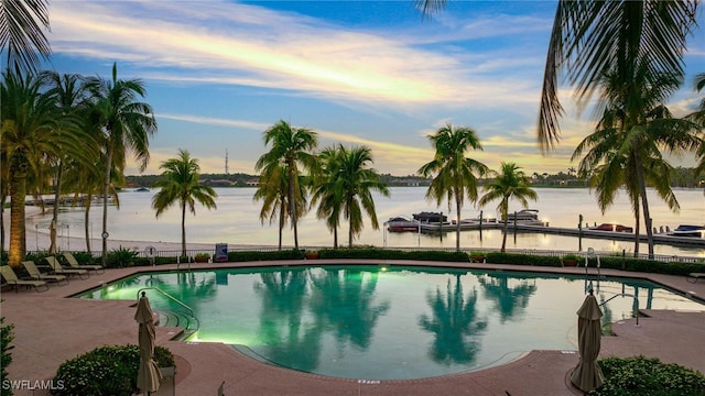 pool at dusk with a boat dock and a patio area