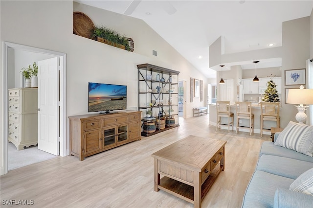 living room featuring ceiling fan, light wood-type flooring, and high vaulted ceiling