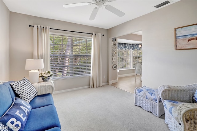 living area with light carpet and ceiling fan