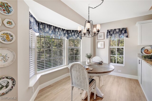 dining space with light hardwood / wood-style flooring and a notable chandelier