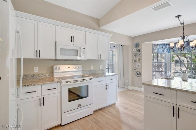 737 Wiggins Lake Dr Unit 201, Naples, FL 34110 - kitchen featuring white appliances, light wood-type flooring, a chandelier, white cabinetry, and baseboards