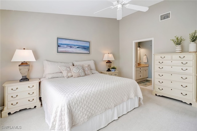 carpeted bedroom with ensuite bathroom and ceiling fan