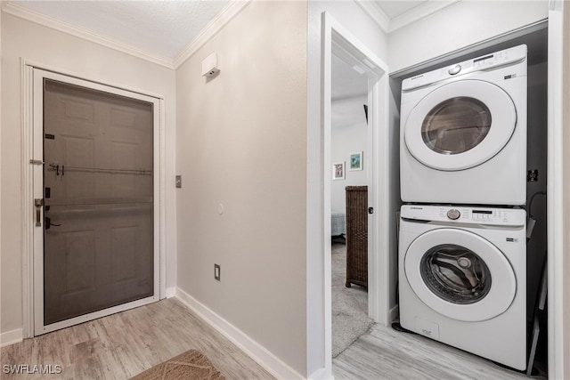 clothes washing area with ornamental molding, a textured ceiling, light hardwood / wood-style flooring, and stacked washer / drying machine