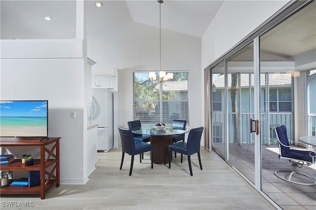 dining space featuring vaulted ceiling, a notable chandelier, and light wood-type flooring