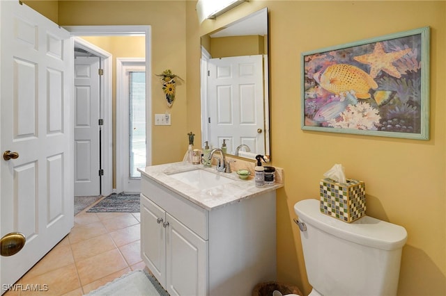 bathroom with tile patterned flooring, toilet, a healthy amount of sunlight, and vanity