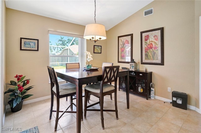 dining area with a notable chandelier, lofted ceiling, and light tile patterned flooring