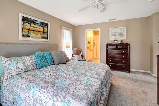 bedroom with ceiling fan, light carpet, and ensuite bath