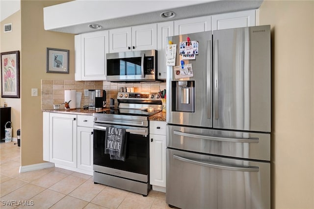 kitchen featuring light tile patterned flooring, backsplash, appliances with stainless steel finishes, stone counters, and white cabinets