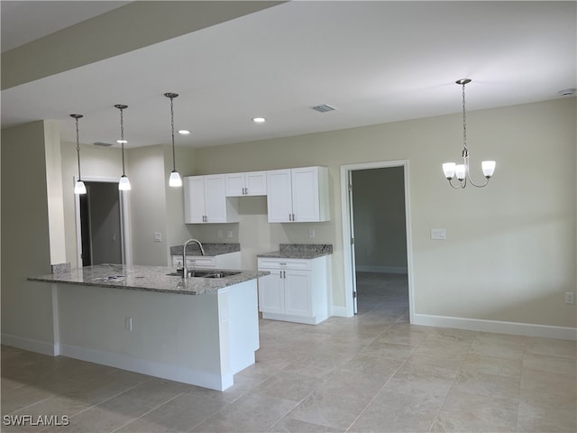 kitchen with light tile patterned floors, sink, stone countertops, and white cabinets