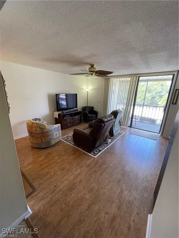 living room with ceiling fan, wood-type flooring, and a textured ceiling