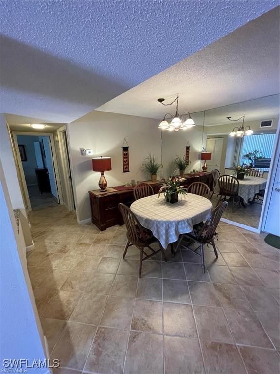 dining room featuring a notable chandelier, tile patterned floors, and a textured ceiling