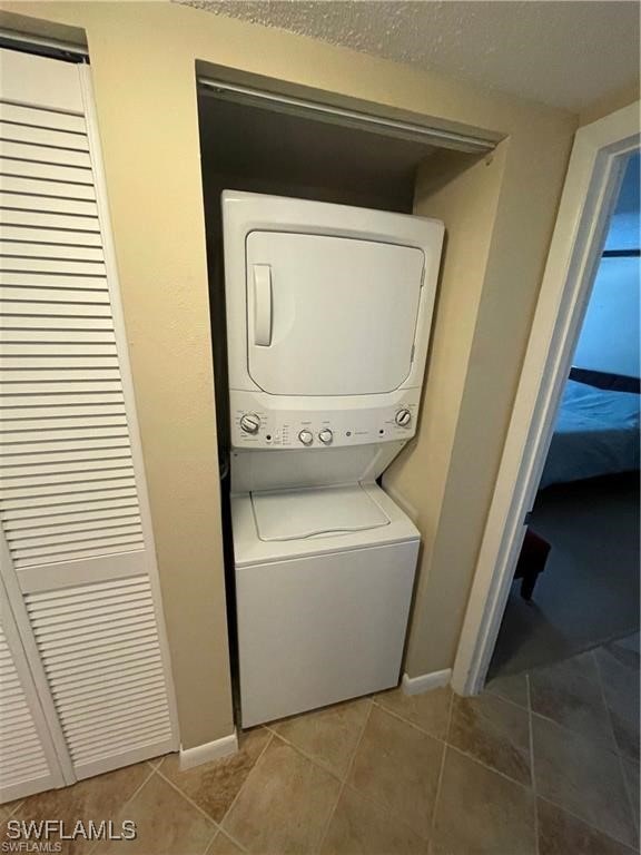 washroom with stacked washer and dryer and tile patterned flooring