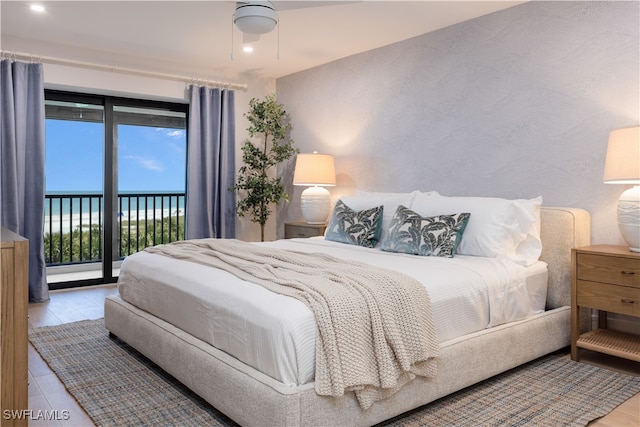 bedroom with a water view, ceiling fan, light wood-type flooring, and access to exterior