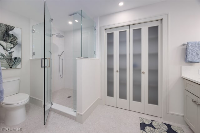 bathroom with vanity, toilet, and a shower with door